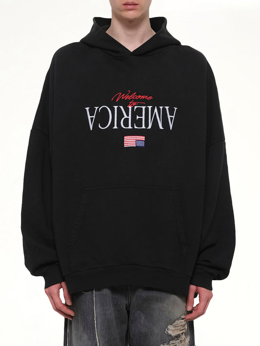 Image of a model wearing Outerwear. Product name - Welcome To America Hooligan Hoodie in Black colour by brand - WILLY CHAVARRIA