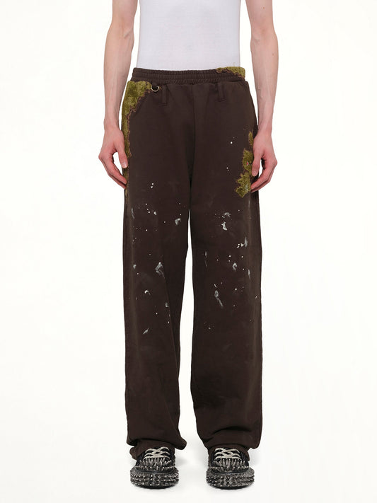 Image of a model wearing Pants. Product name - Moss-Grown Embroidery Sweat Pants in Brown colour by brand - DOUBLET