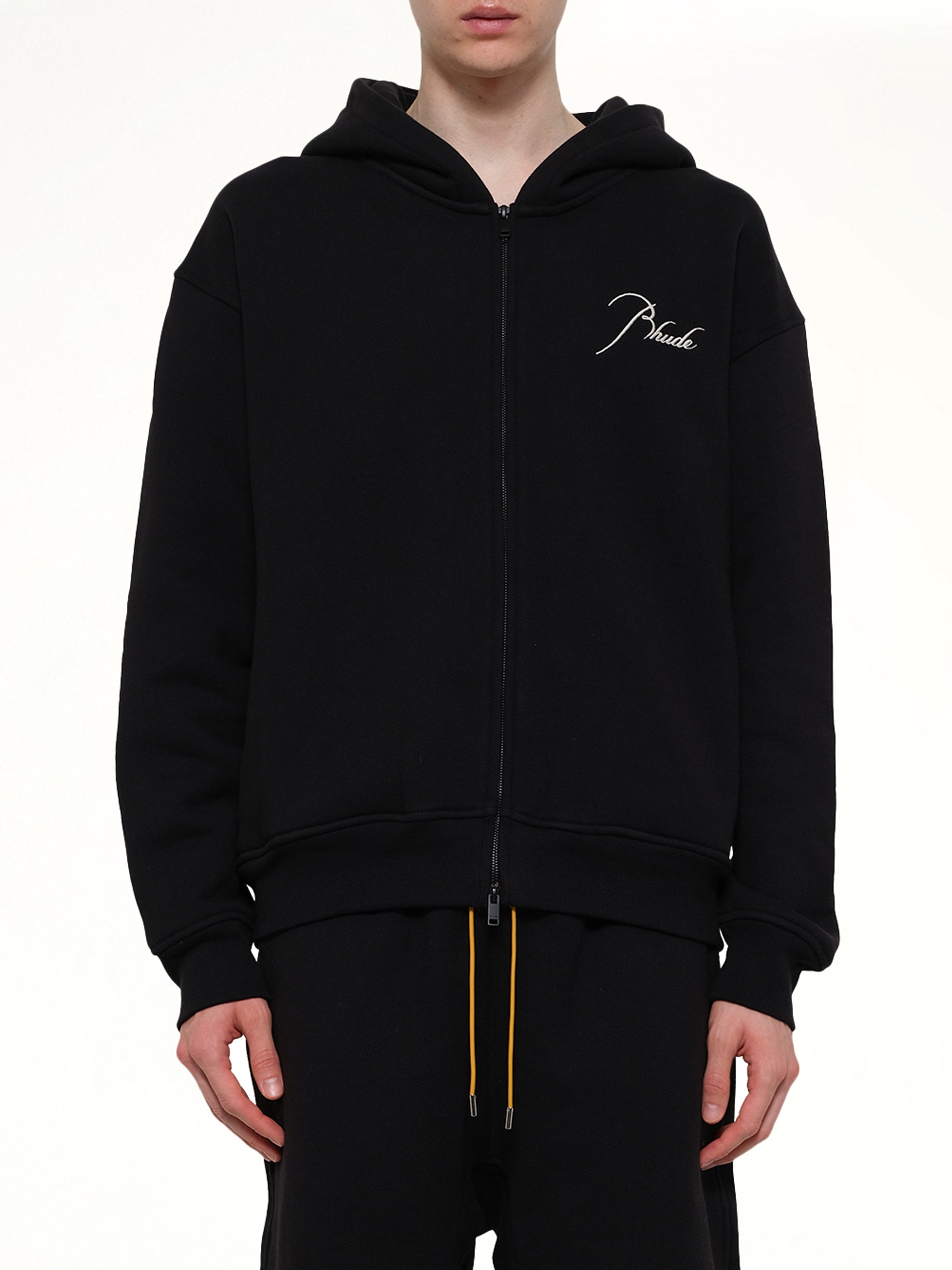 Image of a model wearing Outerwear. Product name - Classique Zip Up Hoodie in Black colour by brand - RHUDE