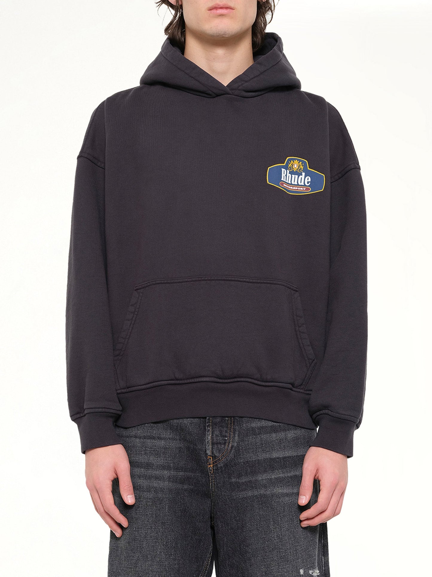Image of a model wearing Outerwear. Product name - Racing Crest Hoodie in Black colour by brand - RHUDE