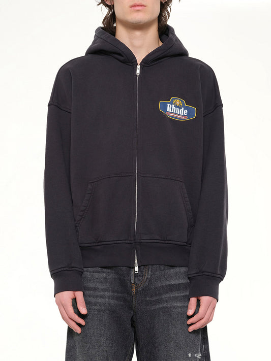 Image of a model wearing Outerwear. Product name - Racing Crest Zip-Up Hoodie in Black colour by brand - RHUDE