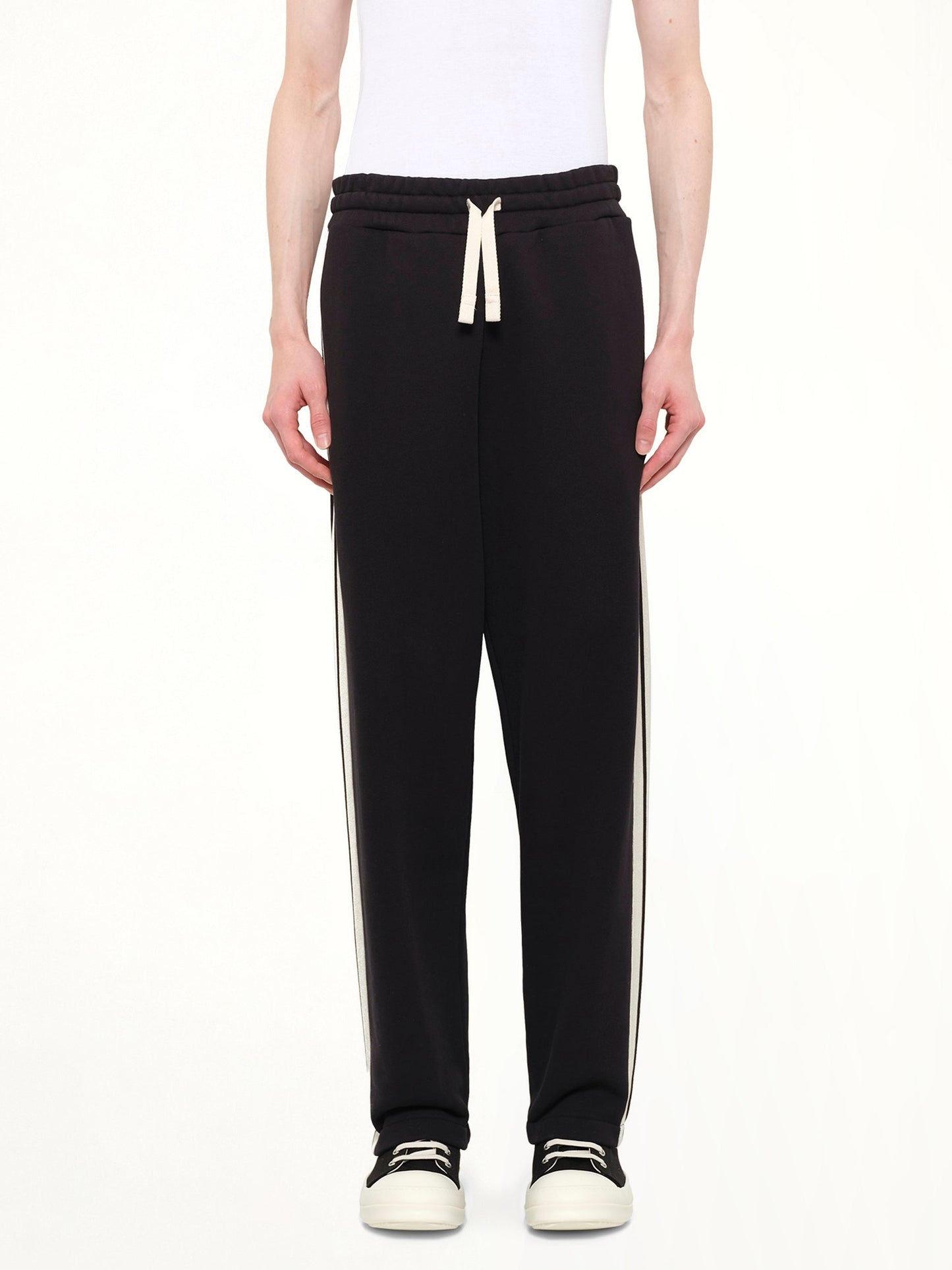 Image of a model wearing Pants. Product name - Back Curved Logo Sweatpants in Black colour by brand - PALM ANGELS