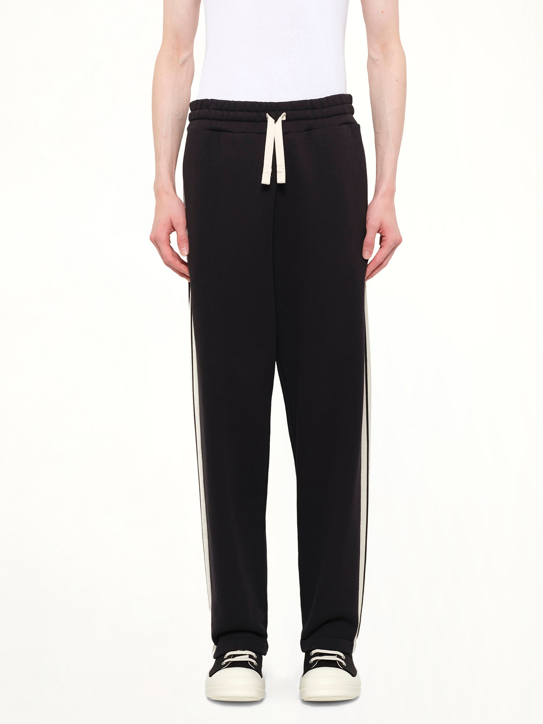 Image of a model wearing Pants. Product name - Back Curved Logo Sweatpants in Black colour by brand - PALM ANGELS