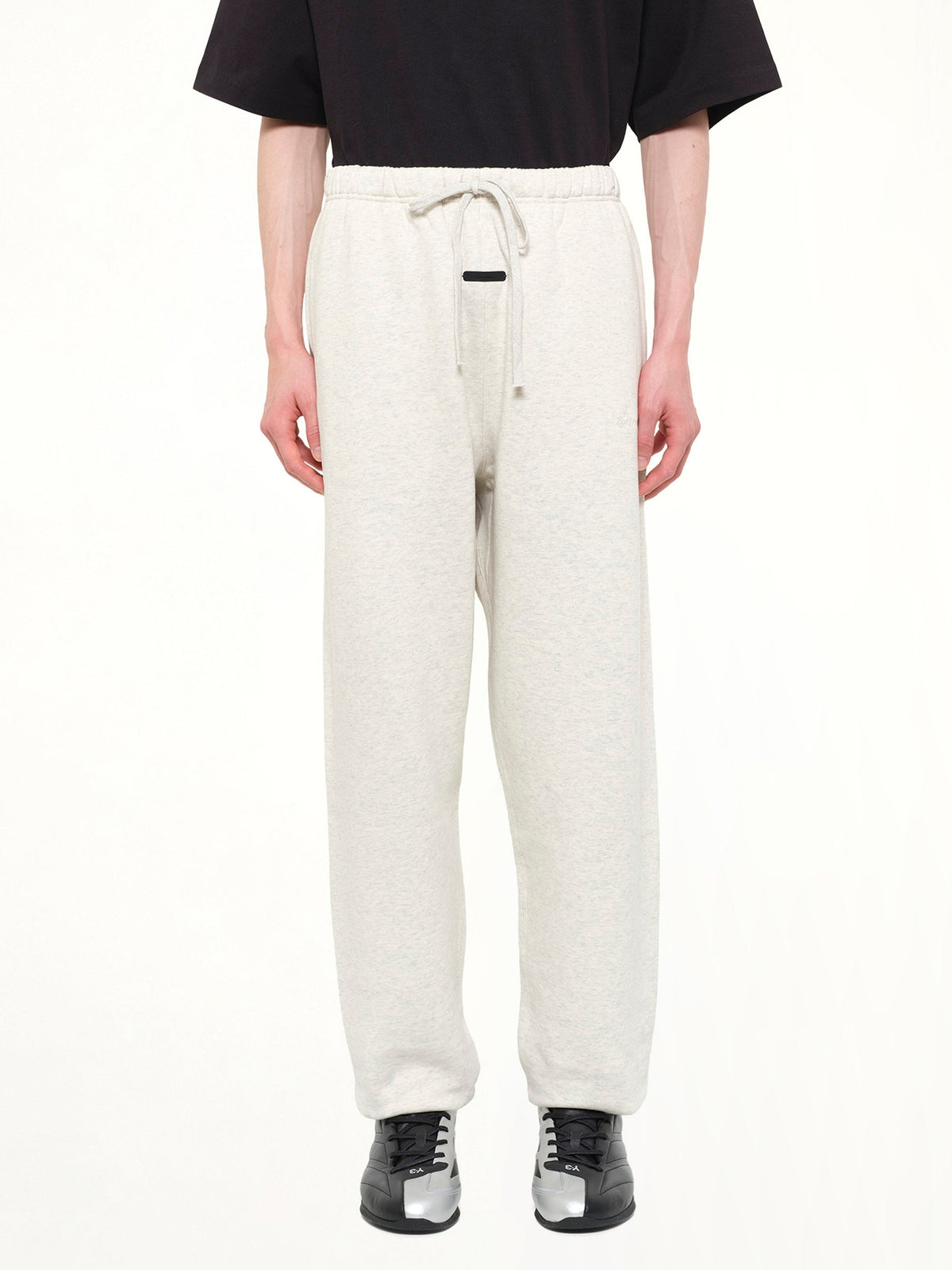 Image of a model wearing Pants. Product name - Signature Classic Sweatpant in White colour by brand - FEAR OF GOD ESSENTIALS