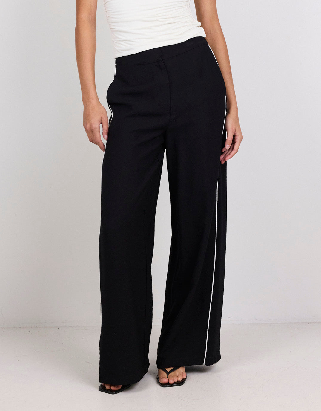 Image of a model wearing Pants. Product name - Exception Piped Side Pants Black in Black colour by brand - Among The Brave