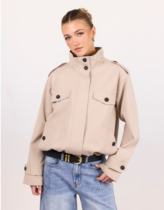 Image of a model wearing Outerwear. Product name - Squad Funnel Neck Trench Jacket Taupe in Taupe colour by brand - Among The Brave