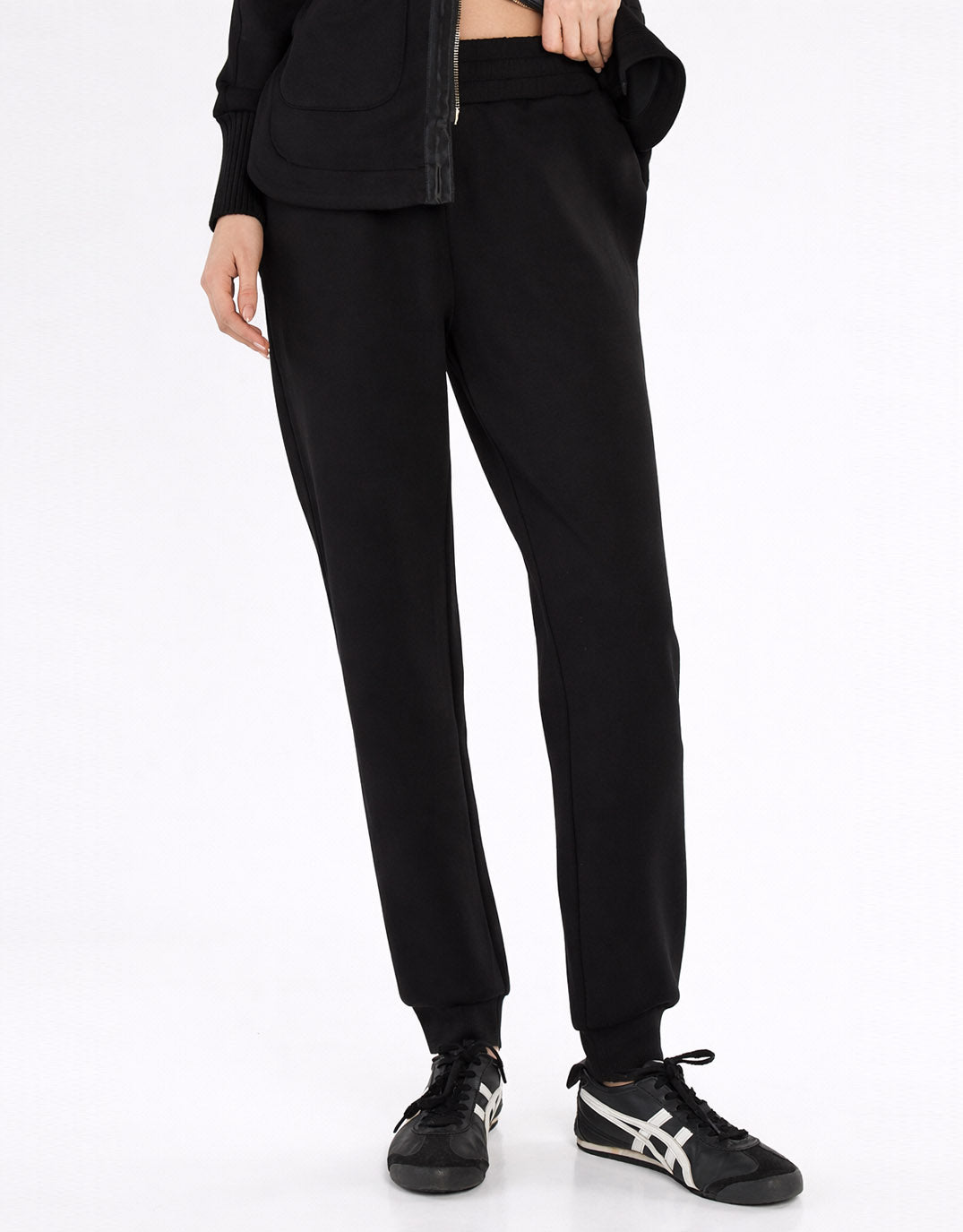 Image of a model wearing Pants. Product name - Sabina Trackpant Black in Black colour by brand - Betty Basics