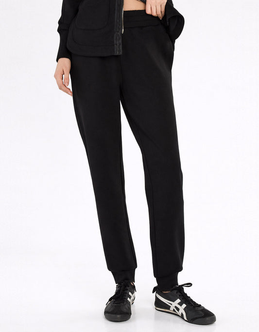 Image of a model wearing Pants. Product name - Sabina Trackpant Black in Black colour by brand - Betty Basics