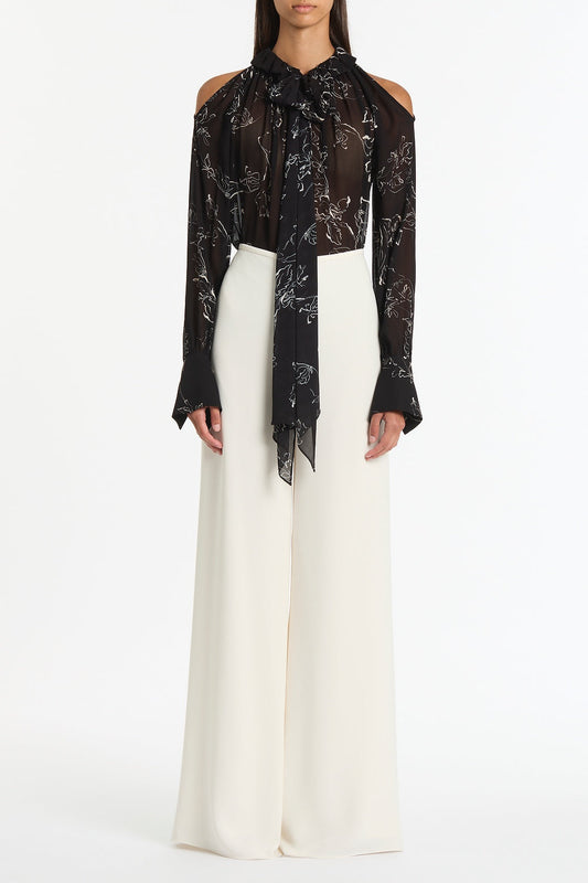 Image of a model wearing Tops. Product name - Black Linear Floral Ruffle Blouse in Black colour by brand - Carla Zampatti