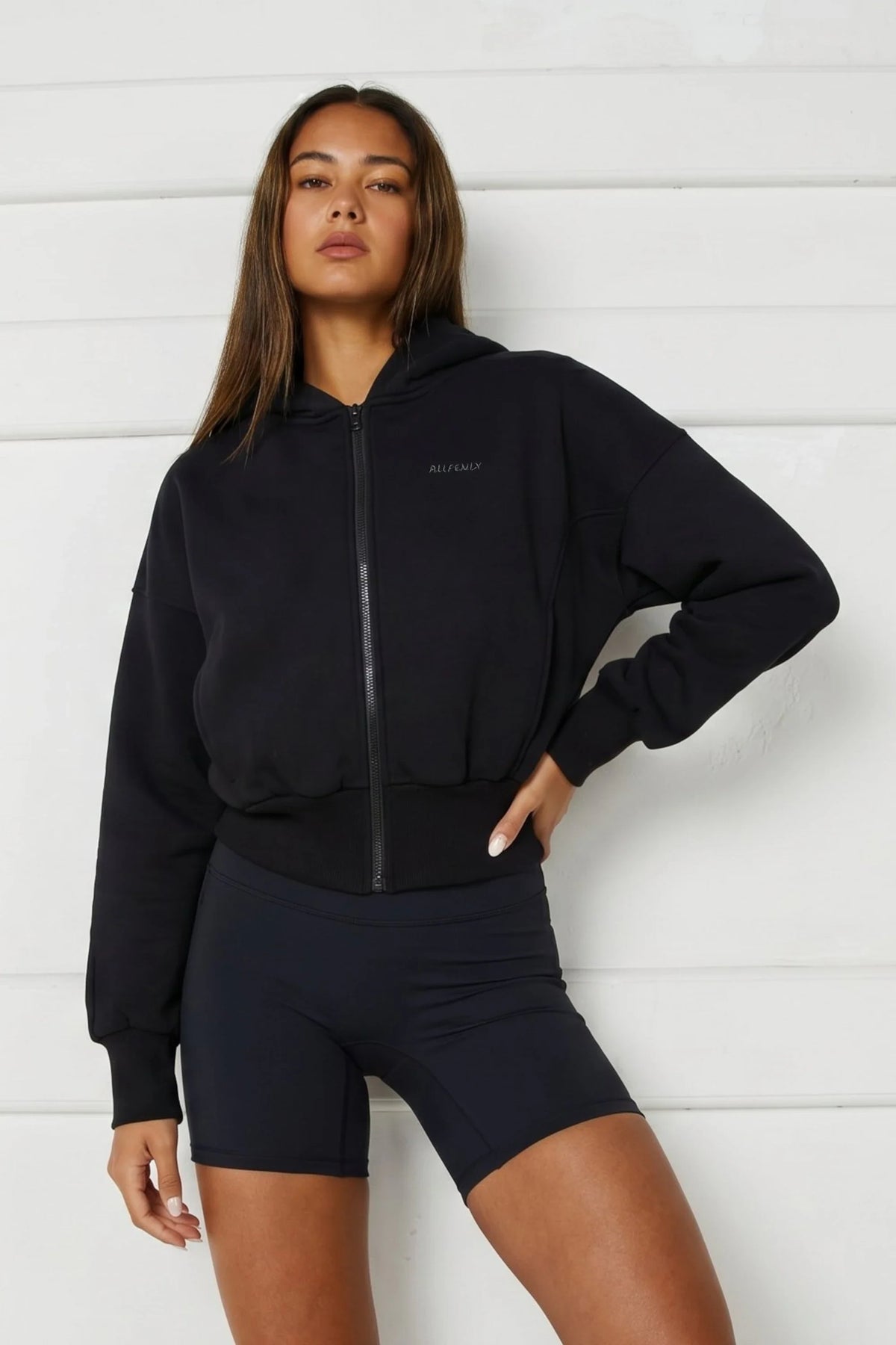 Image of a model wearing Outerwear. Product name - Cropped Zip Hoodie in Black colour by brand - All Fenix