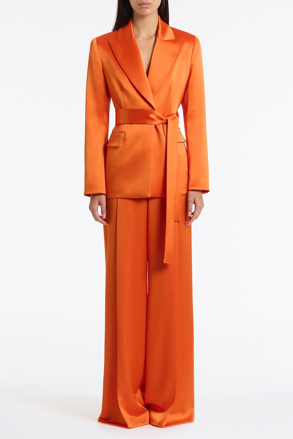 Image of a model wearing Pants. Product name - Clementine Satin Acetate Deep Pleat Pant in Orange colour by brand - Carla Zampatti