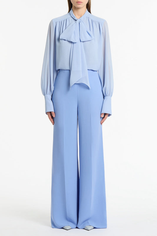 Image of a model wearing Pants. Product name - Cornflower Crepe High Waisted Wide Leg Pant in Blue colour by brand - Carla Zampatti