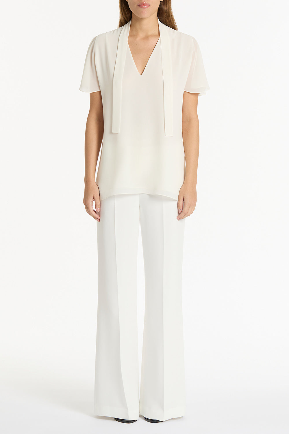 Image of a model wearing Tops. Product name - Cream Georgette Fluted Tie Top in Cream colour by brand - Carla Zampatti
