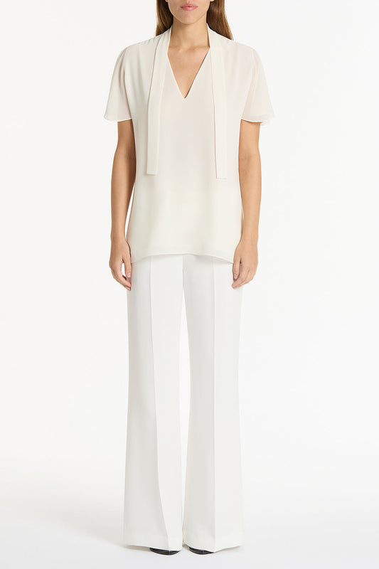 Image of a model wearing Tops. Product name - Cream Georgette Fluted Tie Top in Cream colour by brand - Carla Zampatti
