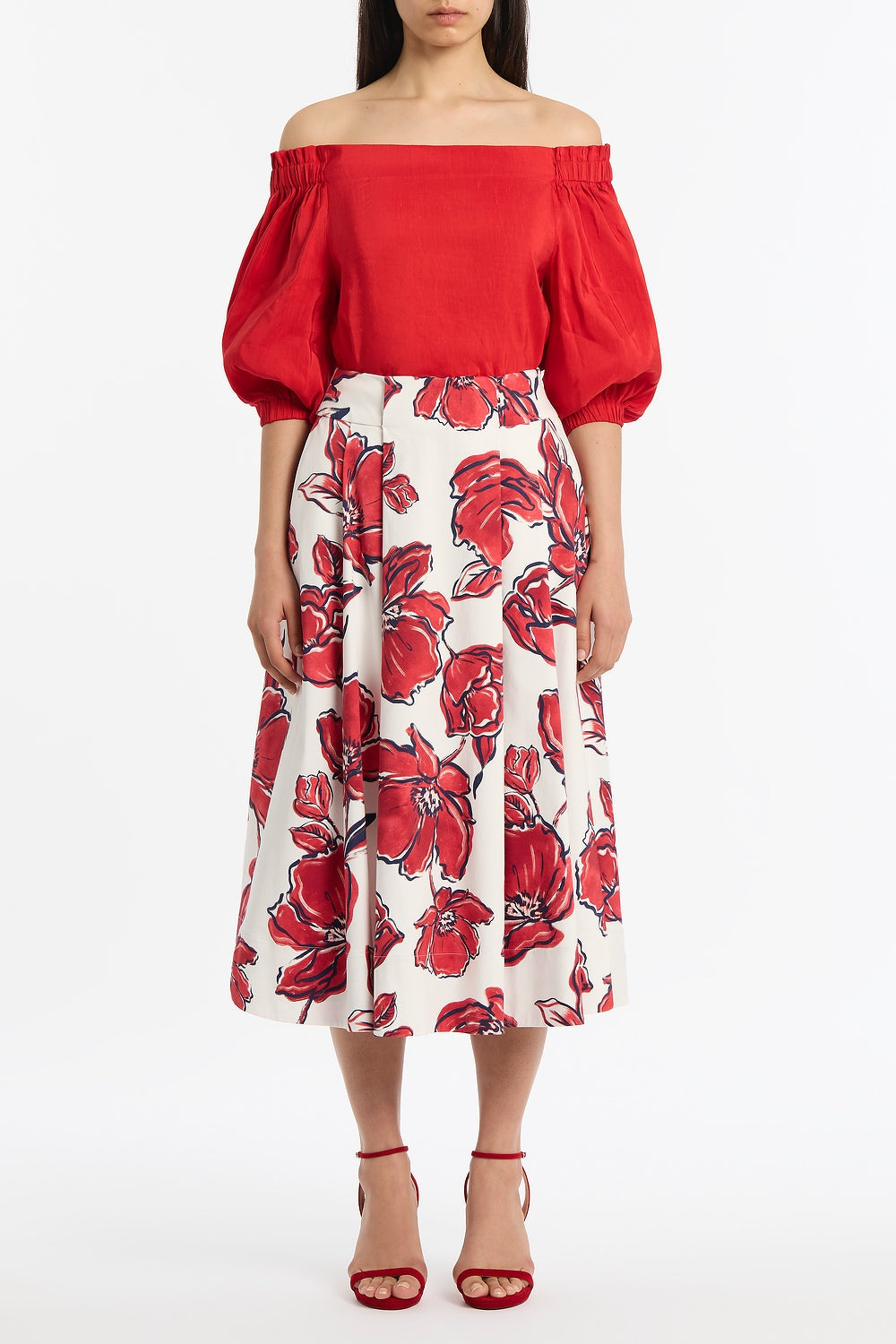 Image of a model wearing Skirts. Product name - Crimson Bouquet Sateen Pleat Detail Skirt in Red colour by brand - Carla Zampatti