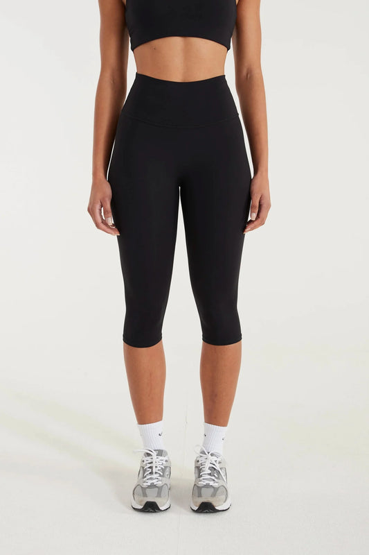Image of a model wearing Pants. Product name - ALLFENIX CloudCore Capri Legging in Black colour by brand - All Fenix