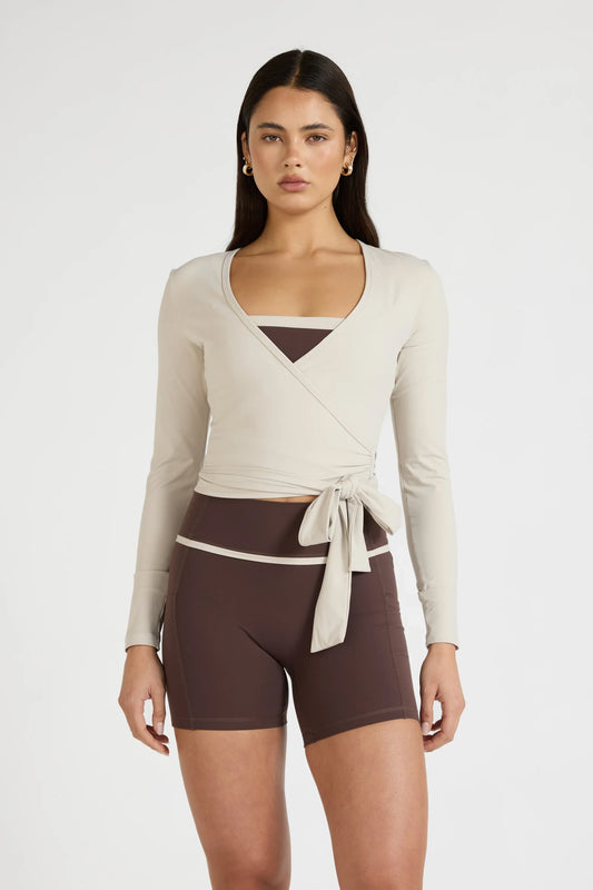 Image of a model wearing Tops. Product name - ALLFENIX CloudCore Lite Long Sleeve Wrap Top in Stone colour by brand - All Fenix