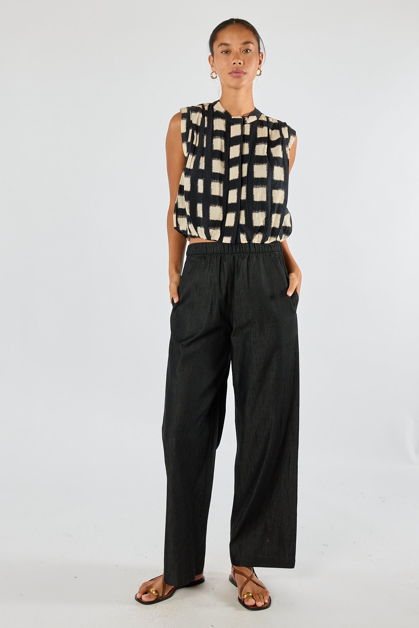 Image of a model wearing Tops. Product name - Itami Bloc S/Less Top Black in Black colour by brand - Itami Division