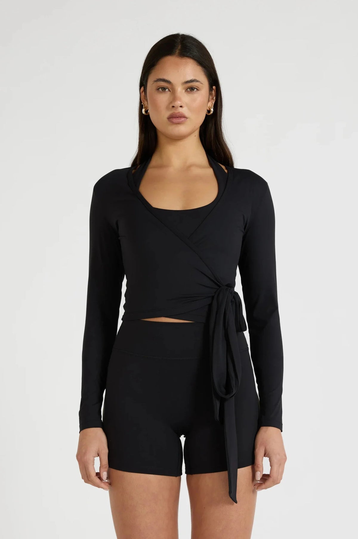 Image of a model wearing Tops. Product name - ALLFENIX CloudCore Lite Long Sleeve Wrap Top in Black colour by brand - All Fenix
