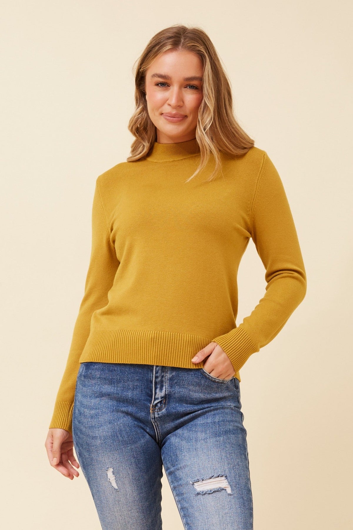Image of a model wearing Tops. Product name - PETUNIA TURTLE NECK KNIT PULLOVER in Mustard colour by brand - Caroline Morgan Australia