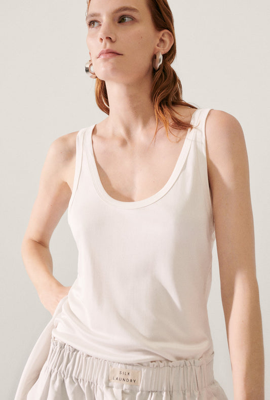 Image of a model wearing Tops. Product name - Jersey Scoop Tank White in White colour by brand - Silk Laundry