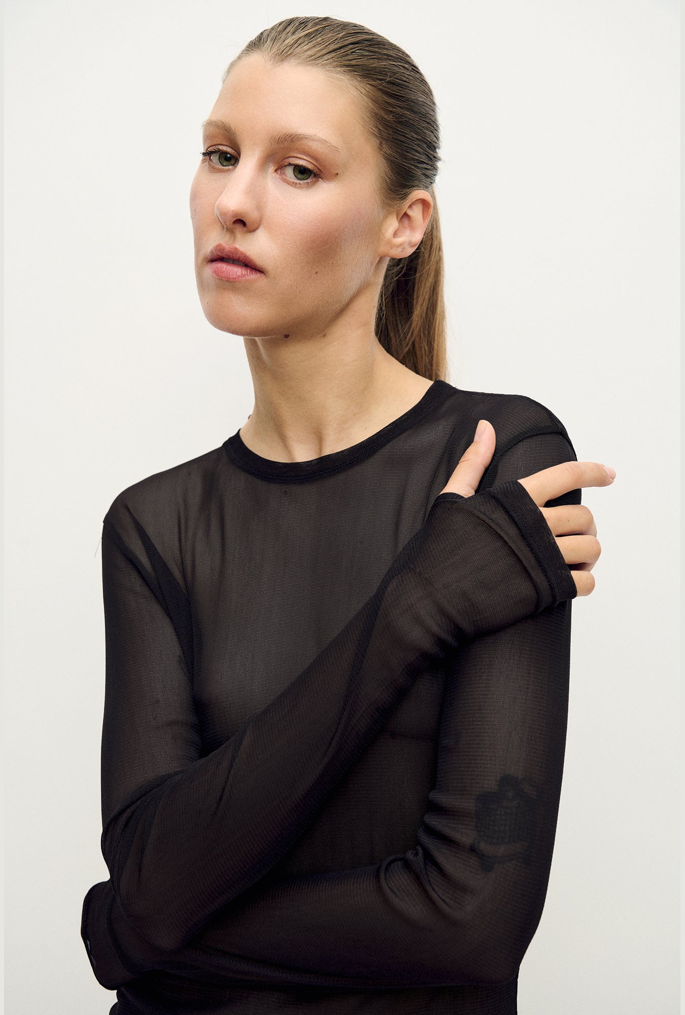 Image of a model wearing Tops. Product name - Mesh Long Sleeve Top Black in Black colour by brand - Silk Laundry
