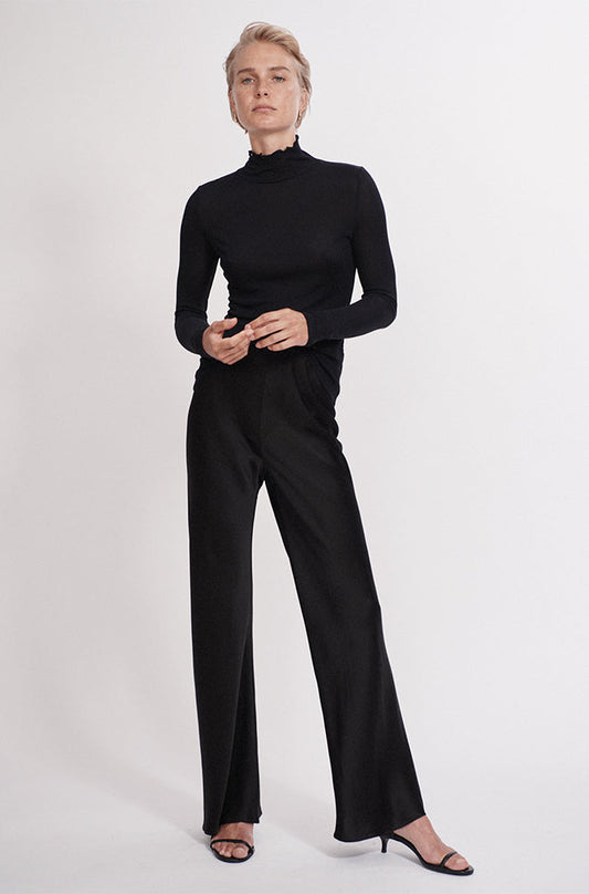 Image of a model wearing Tops. Product name - Ribbed Turtleneck Black in Black colour by brand - Silk Laundry