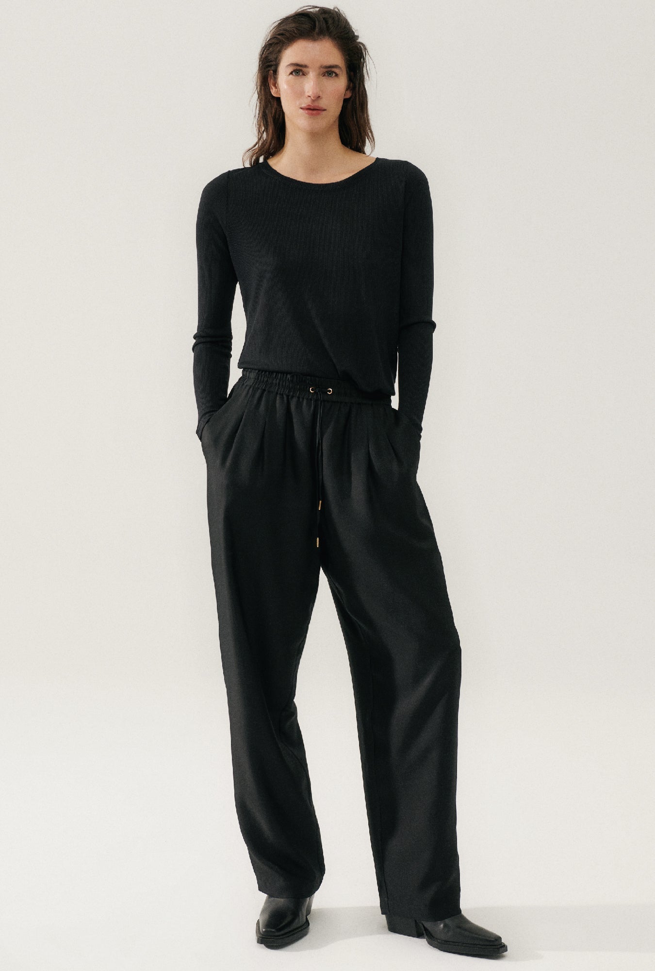Image of a model wearing Tops. Product name - Ribbed Long Sleeve Top Black in Black colour by brand - Silk Laundry