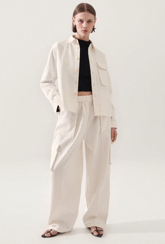 Image of a model wearing Outerwear. Product name - Canvas Overshirt Milk in Natural colour by brand - Silk Laundry