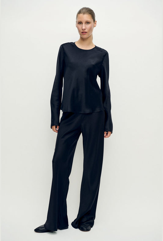 Image of a model wearing Tops. Product name - Long Sleeve Bias Top Black in Black colour by brand - Silk Laundry