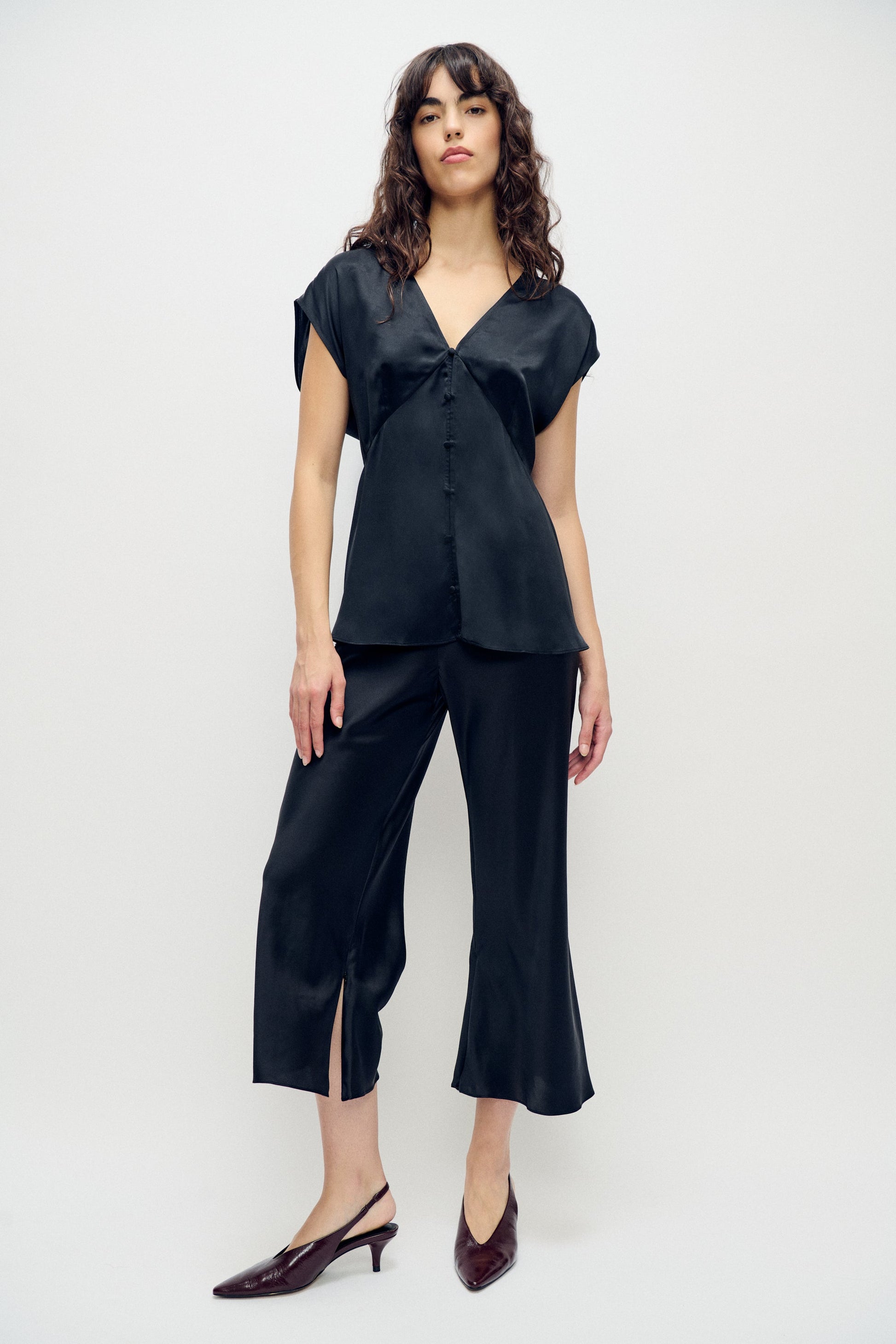 Image of a model wearing Pants. Product name - Cropped Bias Cut Pants Black in Black colour by brand - Silk Laundry