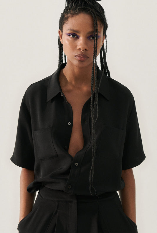 Image of a model wearing Tops. Product name - CDC Short Sleeve Boyfriend Shirt Black in Black colour by brand - Silk Laundry