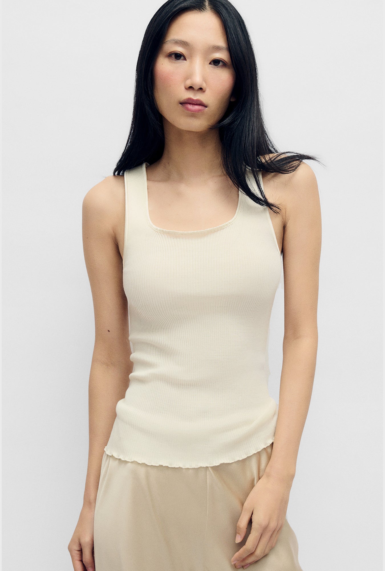Image of a model wearing Tops. Product name - Silk Wool Ribbed Essential Tank White in White colour by brand - Silk Laundry