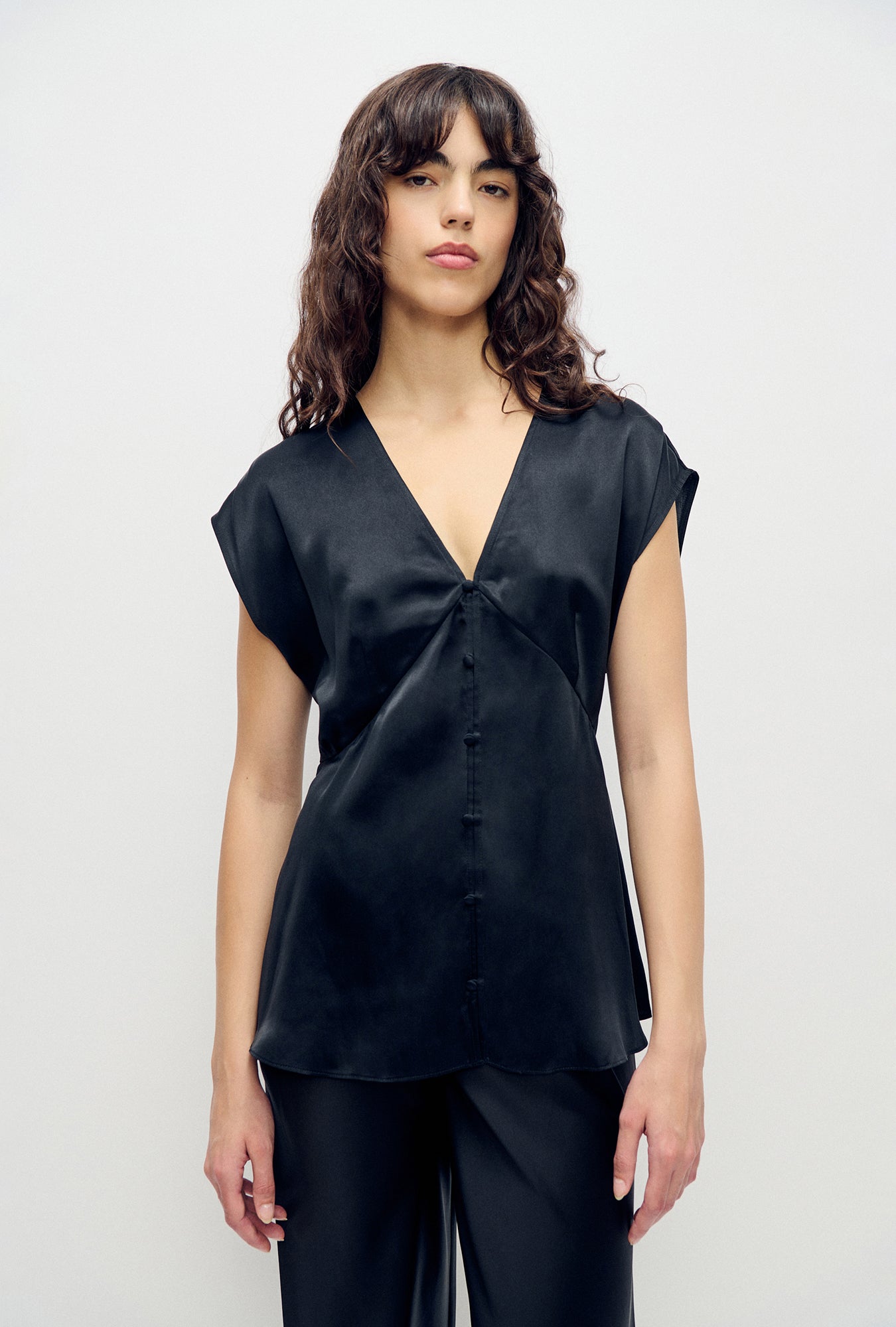 Image of a model wearing Tops. Product name - V-Neck Top Black in Black colour by brand - Silk Laundry