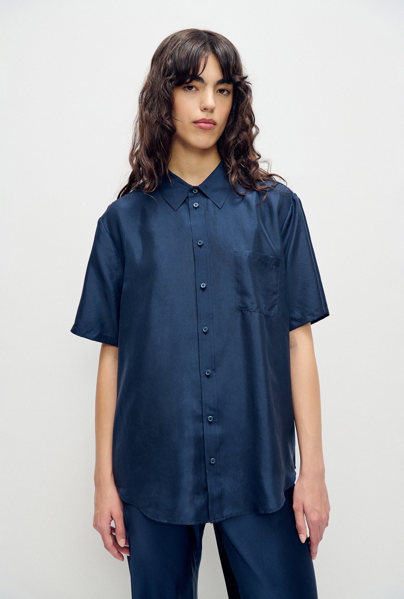 Image of a model wearing Tops. Product name - Habotai Short Sleeve Boyfriend Shirt Midnight in Midnight colour by brand - Silk Laundry