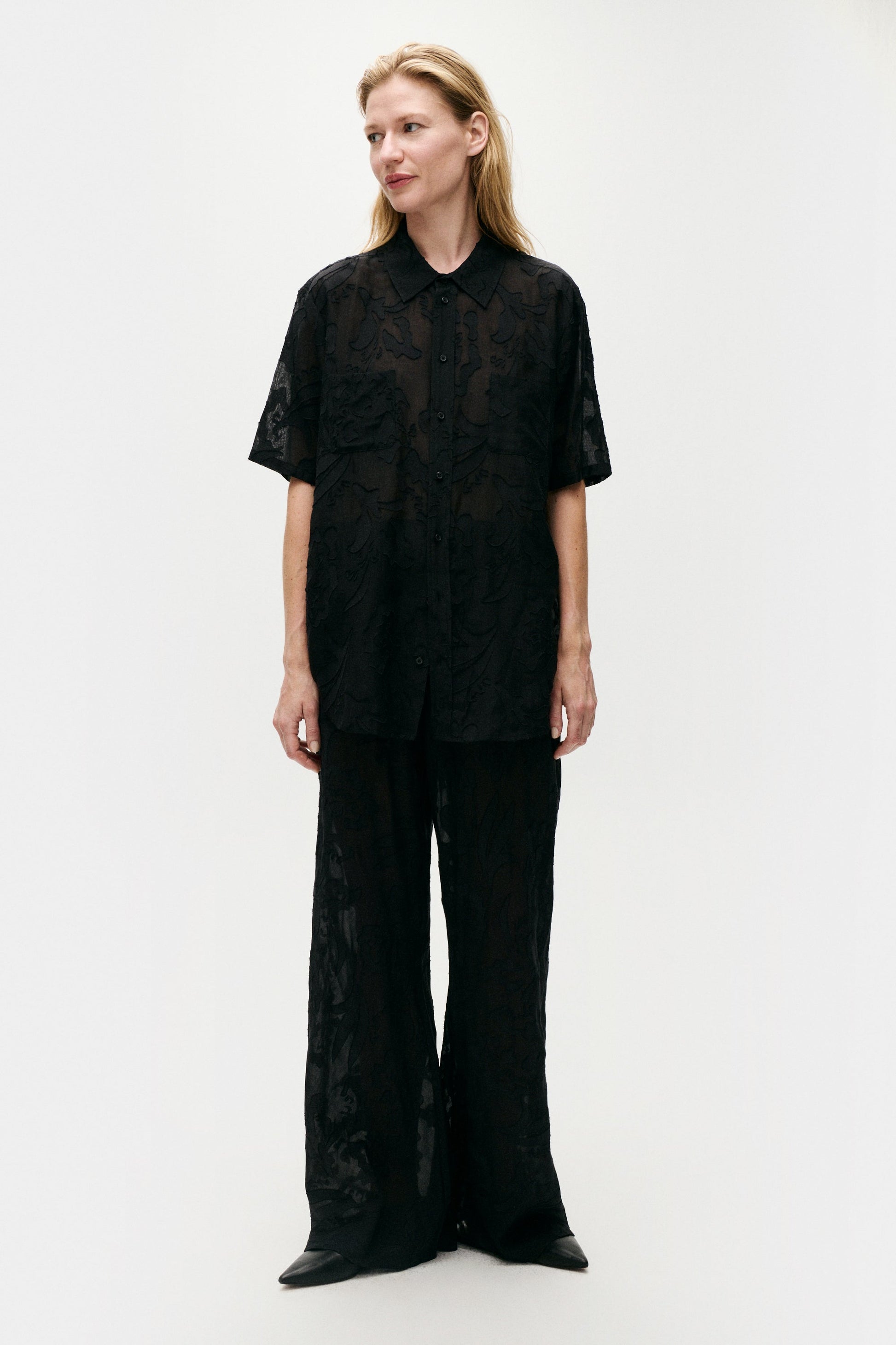 Image of a model wearing Tops. Product name - Clip Silk Short Sleeve Boyfriend Shirt Black in Black colour by brand - Silk Laundry