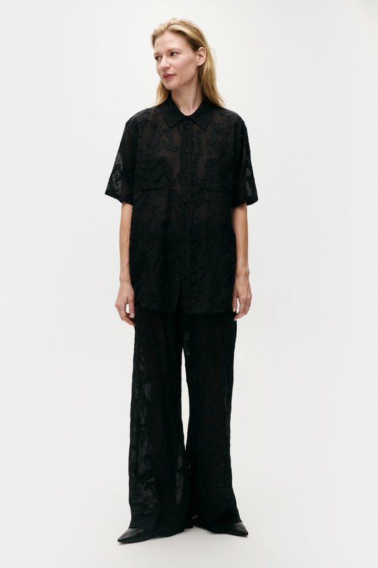 Image of a model wearing Tops. Product name - Clip Silk Short Sleeve Boyfriend Shirt Black in Black colour by brand - Silk Laundry