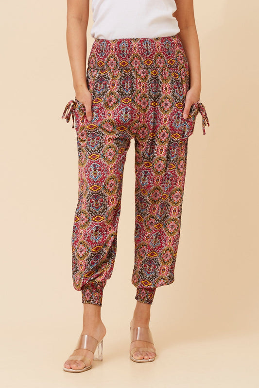 Image of a model wearing Pants. Product name - ABSTRACT PRINT BOHO HAREM PANTS in Multi Red colour by brand - CKM