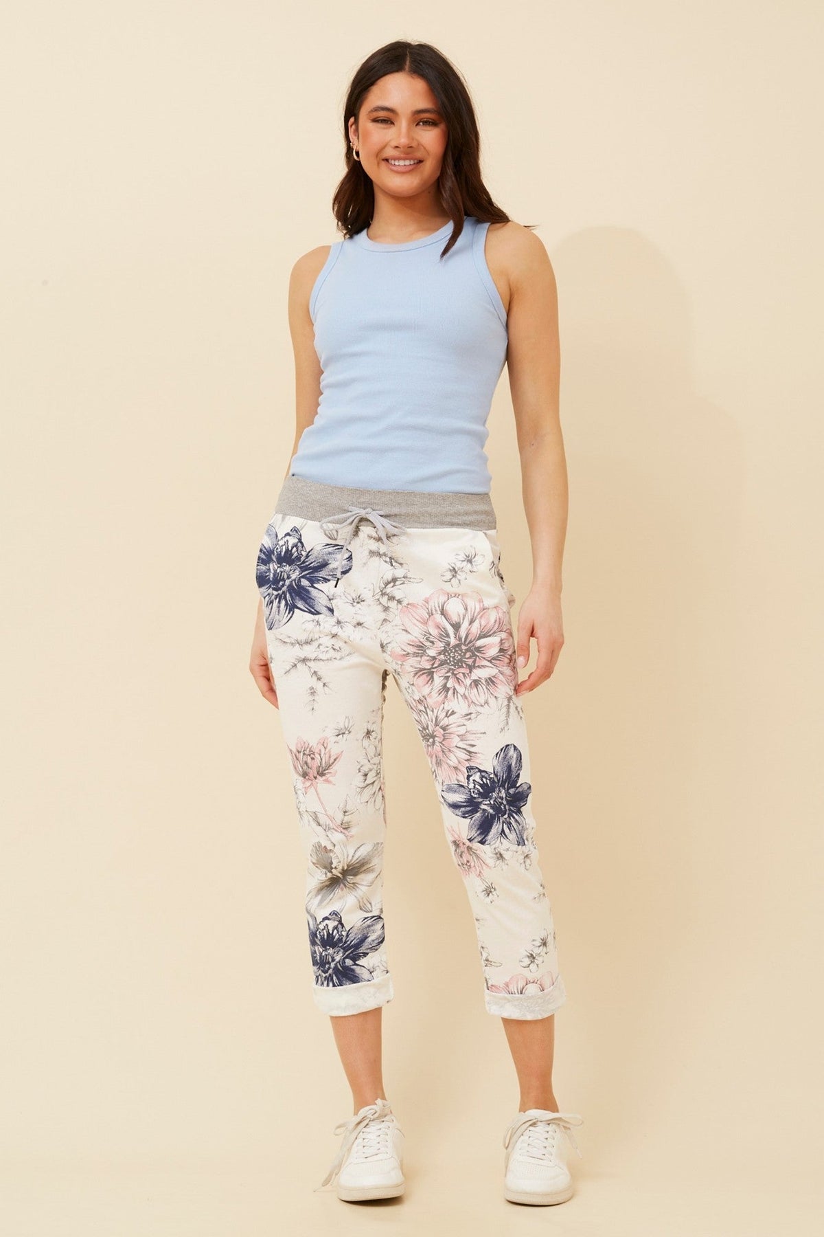 Image of a model wearing Pants. Product name - GINNA FLORAL JOGGER PANTS in Petal Pink colour by brand - BOTTEGA MODA