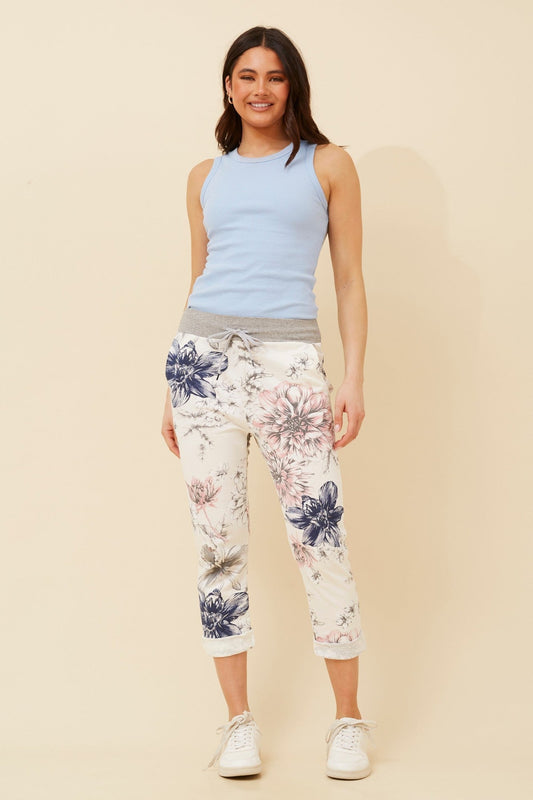 Image of a model wearing Pants. Product name - GINNA FLORAL JOGGER PANTS in Petal Pink colour by brand - BOTTEGA MODA