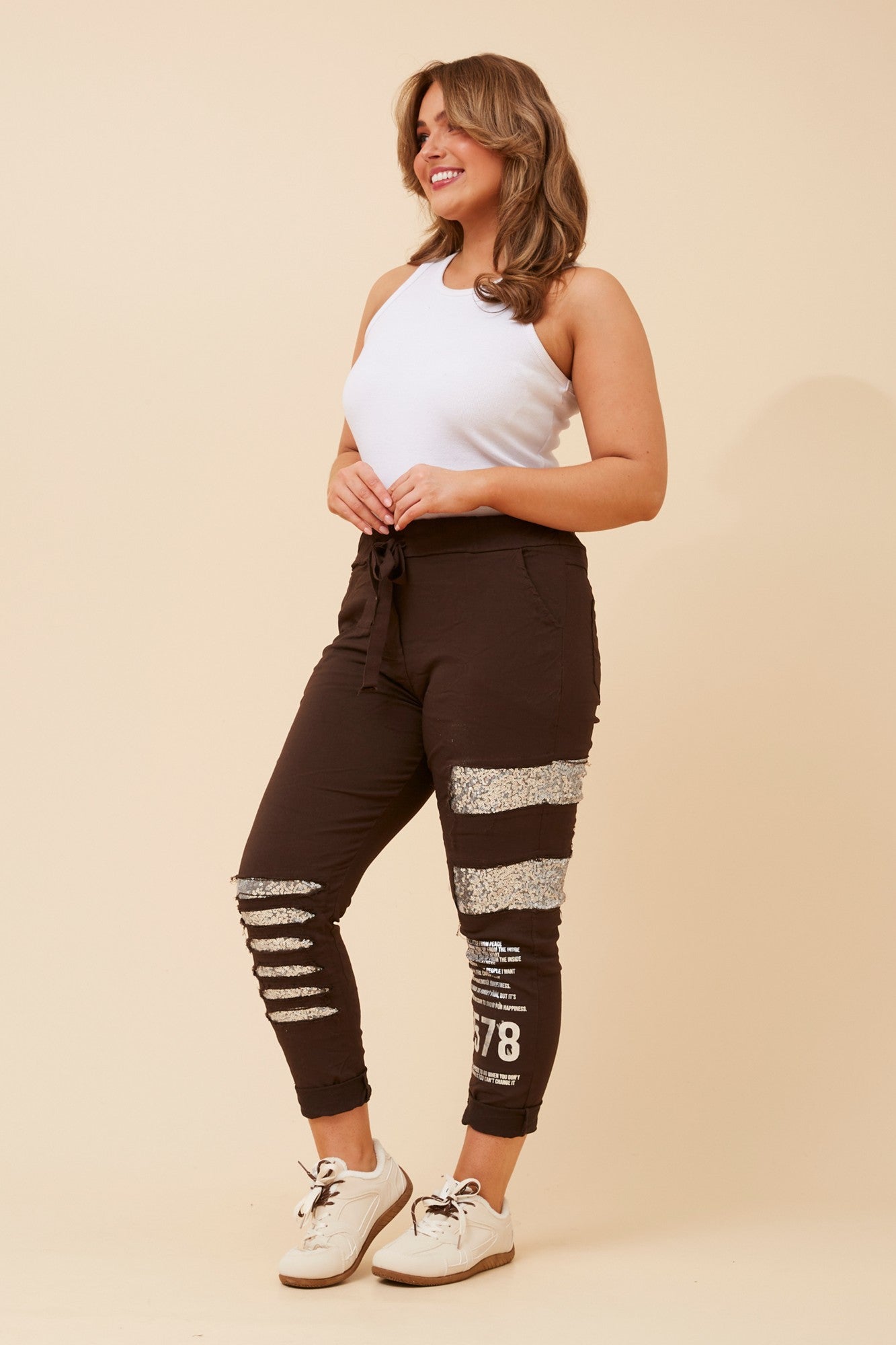 Image of a model wearing Pants. Product name - JANJA SEQUIN JOGGER PANTS in Khaki colour by brand - BOTTEGA MODA