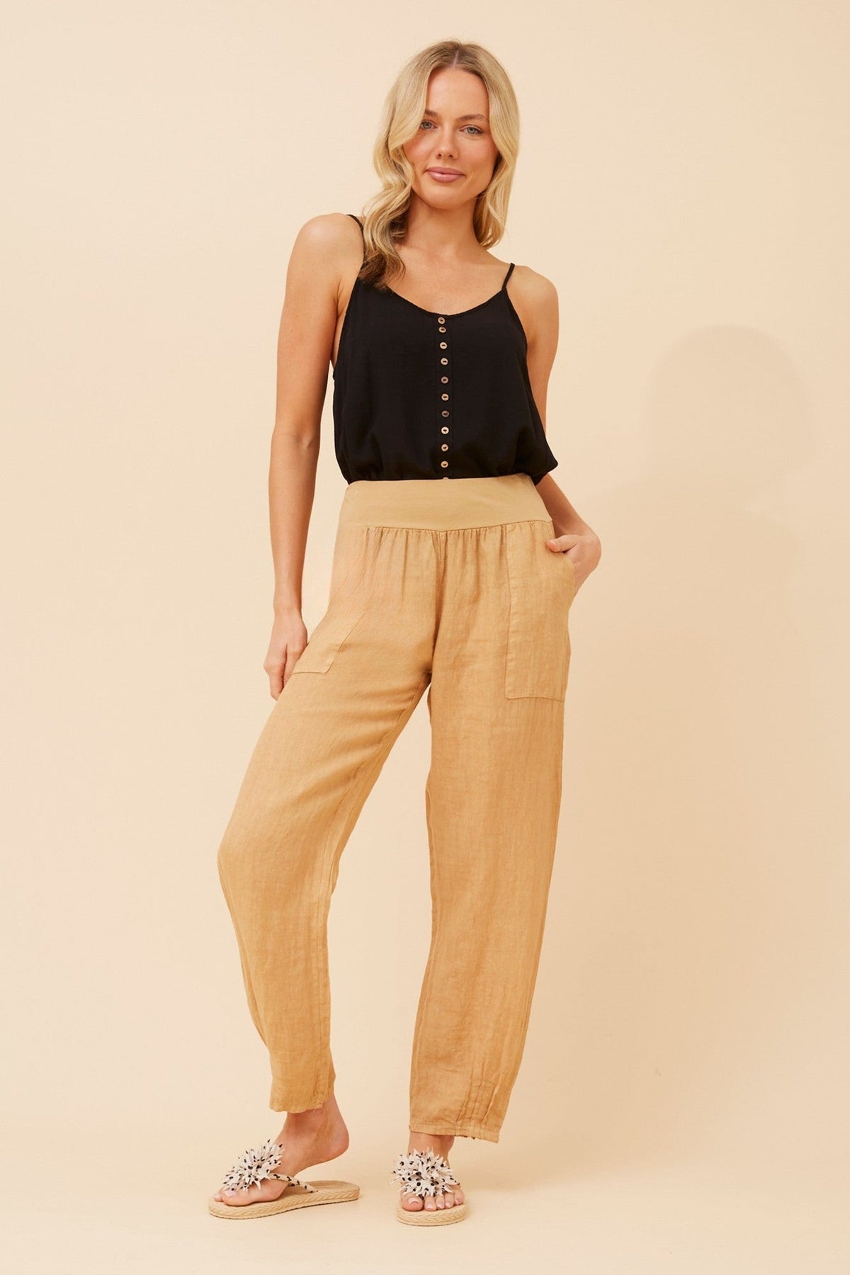 Image of a model wearing Pants. Product name - FINN SOLID LINEN PANTS in Biscuit colour by brand - BOTTEGA MODA