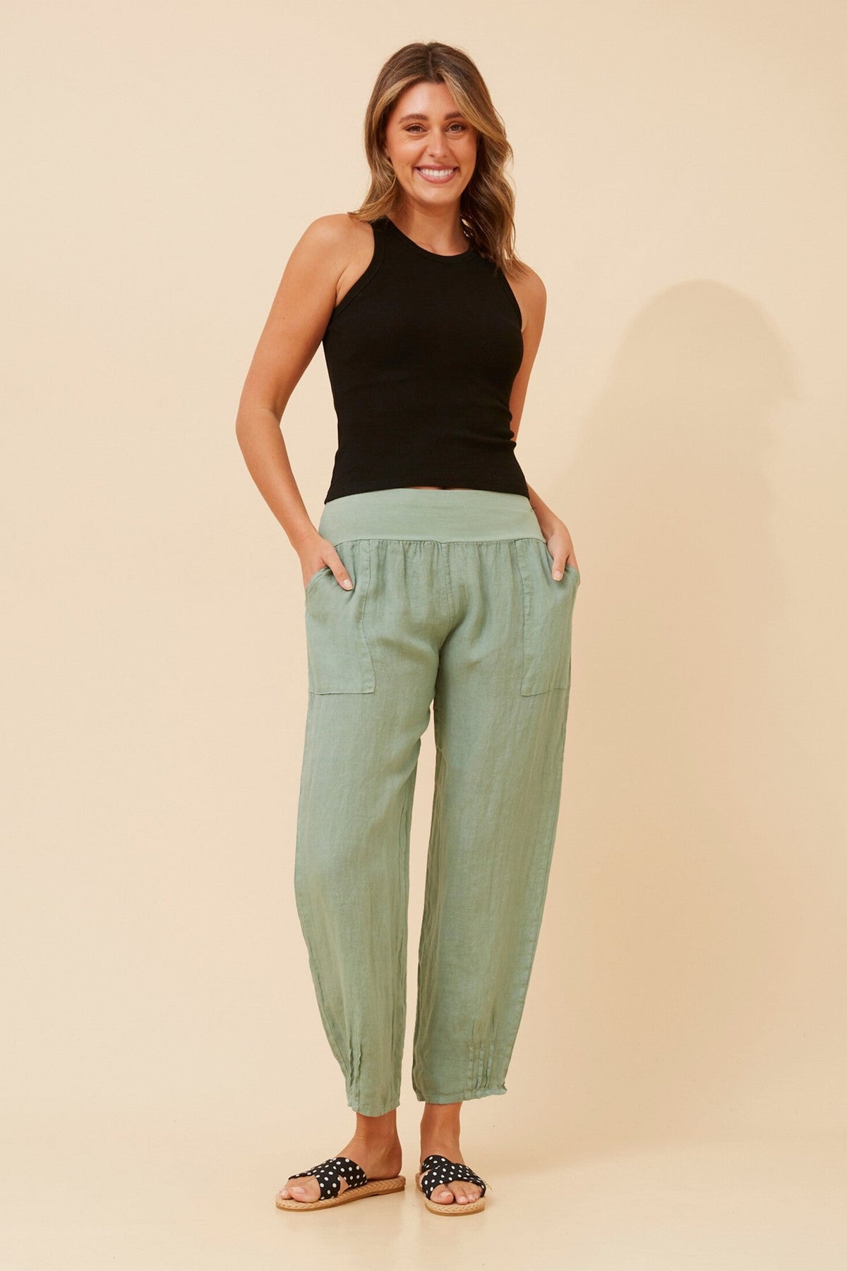 Image of a model wearing Pants. Product name - FINN SOLID LINEN PANTS in Sage colour by brand - BOTTEGA MODA