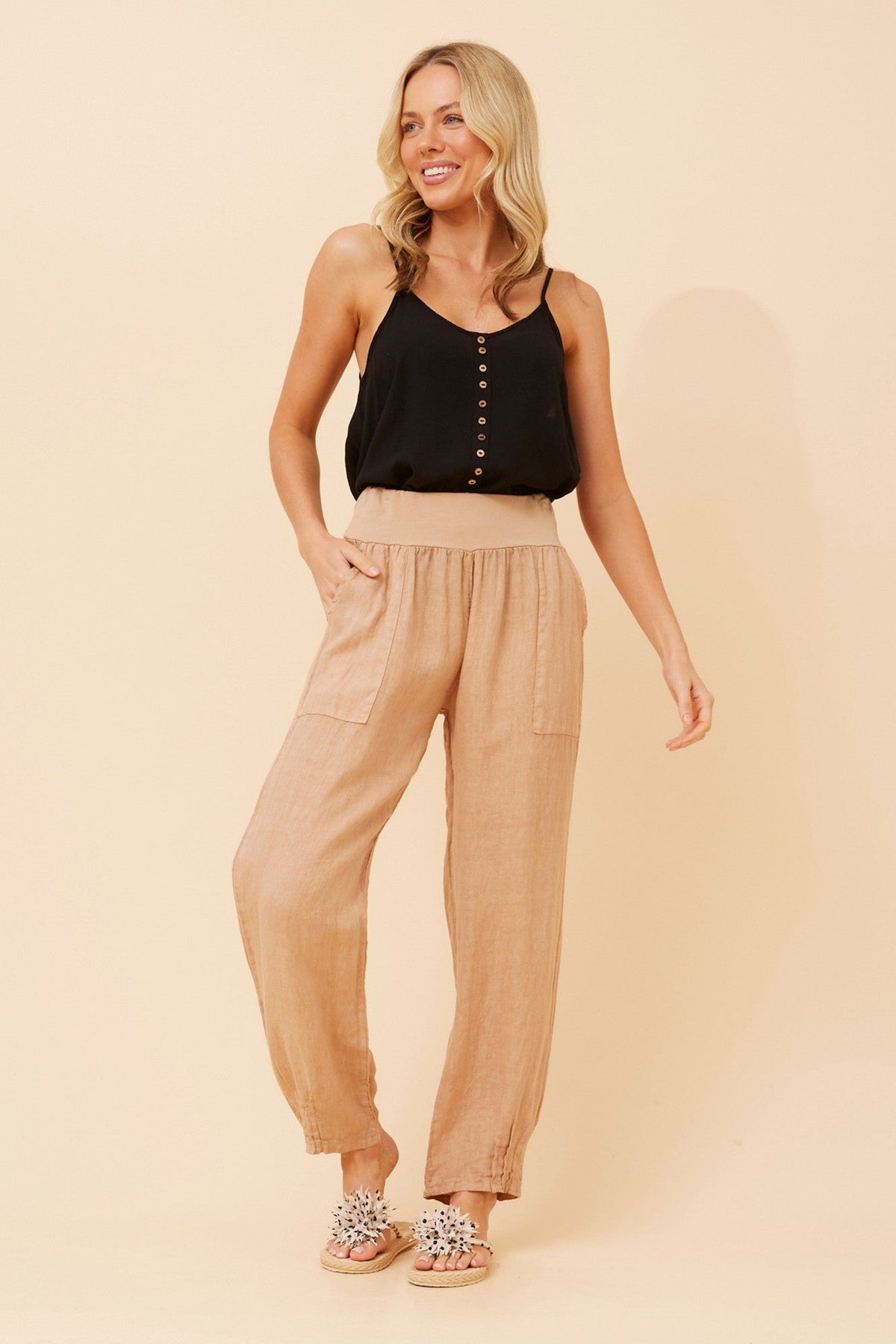 Image of a model wearing Pants. Product name - FINN SOLID LINEN PANTS in Toffee colour by brand - BOTTEGA MODA