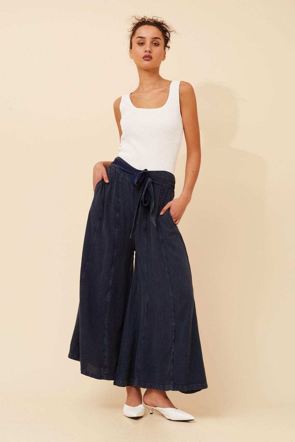 Image of a model wearing Pants. Product name - ANETTA FLARE LEG PANTS in Dark Denim colour by brand - Caroline Morgan Australia