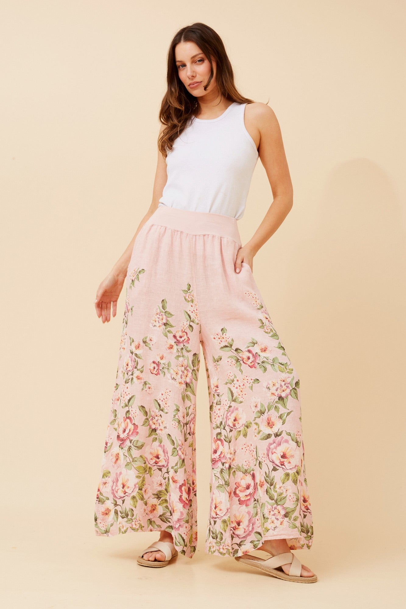 Image of a model wearing Pants. Product name - LEONORA FLORAL WIDE LEG LINEN PANTS in Light Pink colour by brand - BOTTEGA MODA