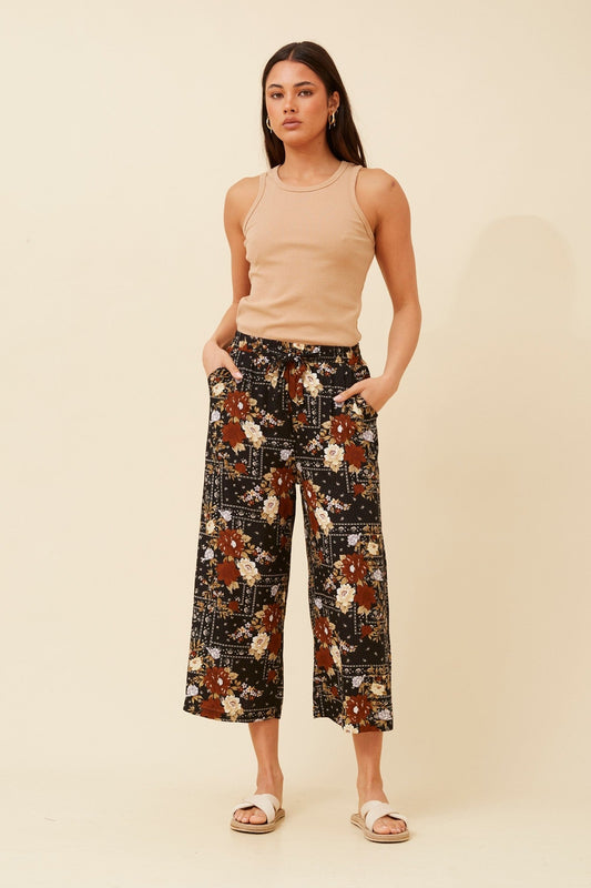 Image of a model wearing Pants. Product name - SUZE FLORAL CULOTTE PANTS in Multi Black colour by brand - Caroline Morgan Australia