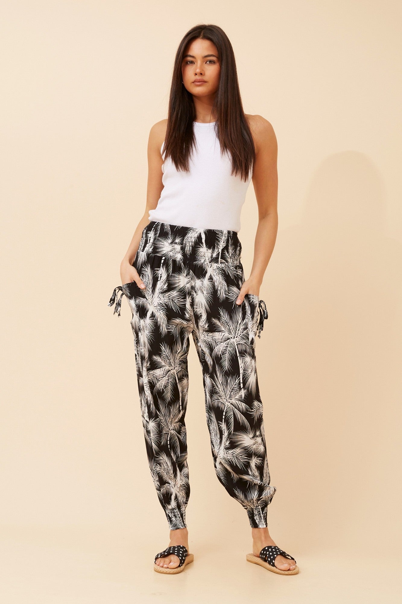 Image of a model wearing Pants. Product name - TROPICAL PRINT HAREM PANTS in Black And White colour by brand - Caroline Morgan Australia