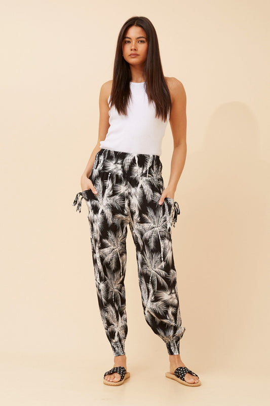 Image of a model wearing Pants. Product name - TROPICAL PRINT HAREM PANTS in Black And White colour by brand - Caroline Morgan Australia