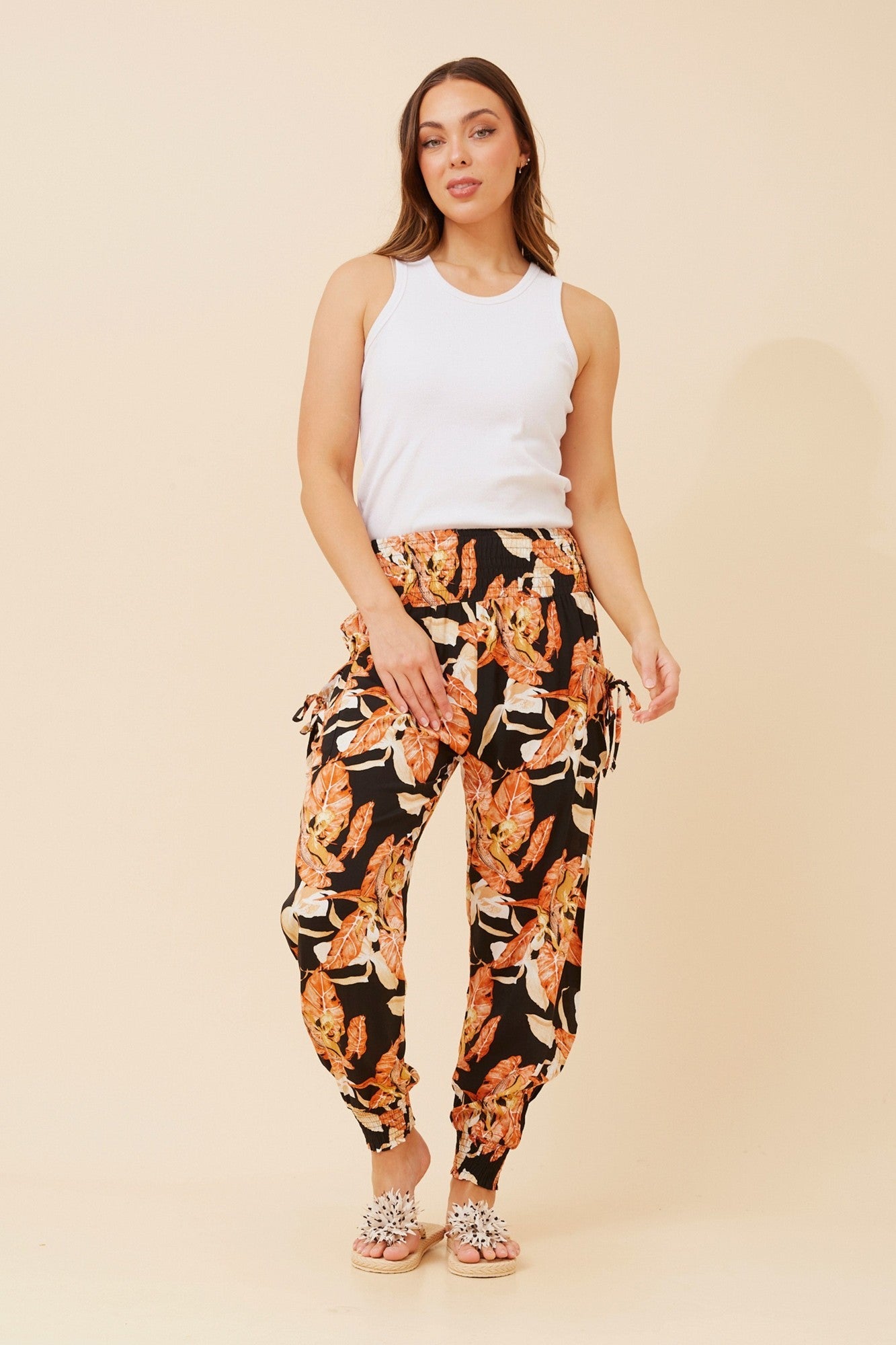 Image of a model wearing Pants. Product name - LEAF PRINT HAREM PANTS in Orange colour by brand - Caroline Morgan Australia
